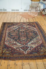 Textured, tattered edge of an Antique Distressed Qashqai rug with geometric border and floral detail.