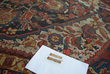 Distressed Qashqai pile, geometric floral motifs and arrowheads in navy, wine red, and gold.