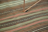 Alternating woven stripes of a vintage Kilim rug in sea foam green, blush, and bronze.