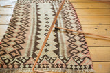 Vintage Kilim rug's geometric stylizations in ivory, blush, and charcoal tones, with fringe.
