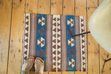 Kilim rug: geometric pinwheel and triangle patterns in brilliant blue, ivory, dark brown, and blush.
