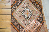 Angled view of the Kilim rug's geometric diamond motif with plum blush and charcoal.