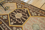 Hand woven Kilim flatweave showcasing blush, bronze, dark brown geometric motifs and wave border.