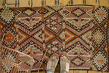 Intricate paneled geometric patterns in plum, beige, and charcoal on a vintage Kilim runner.