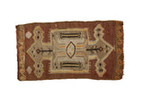 Vintage Kilim rug with geometric medallion, arrow and wave patterns in earth tones.