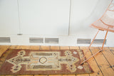 Vintage Kilim rug featuring geometric medallion, arrow, and wave patterns in brown, sand, and orange.