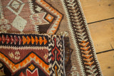 Hand woven Turkish kilim rug's geometric zigzag patterns in brown, orange, and ivory.