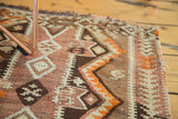 Geometric zigzag motif in tangerine orange, chocolate, and ivory on a handwoven vintage Kilim.