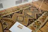 Close-up of vintage hand woven Kilim rug showing blush, brown, saffron geometric patterns.