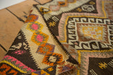 Hand woven texture of vintage Turkish Kilim rug, geometric diamonds in charcoal, pink, orange, yellow.