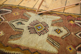 Detail of vintage Turkish kilim showing hourglass medallion with geometric patterns in blush pink and teal.