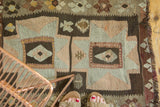 Irregular geometric patterns in powder blue, blush pink, and chocolate brown, with fringed edge.