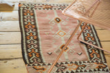Geometric side border of a vintage Kilim rug, showing textured patterns in charcoal, orange, and peach.