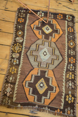 Tangerine orange and chocolate brown stepped medallion with geometric floral border on vintage Kilim rug.
