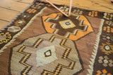 Geometric stepped medallions and pinwheel motifs in tangerine and chocolate brown on a vintage Kilim.