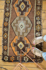 Turkish Kilim rug featuring geometric stepped medallions and floral borders in chocolate brown and tangerine.