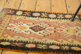 Hand woven vintage Turkish Kilim rug with geometric patterns in blush peach, saffron, and brown.