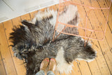 Luxurious angora skin rug texture in soft charcoal, grey, and ivory shades.