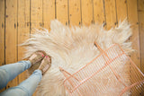 Luxurious ivory Angora skin rug texture, feet in sandals and a rose gold basket.
