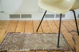 Vintage Jijim rug mat, irregular geometric patterns, frayed edges, in warm tones.