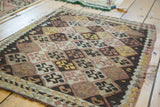 Detail of hand woven Turkish Kilim mat, geometric diamond motif in brown, ivory, and faded yellow.