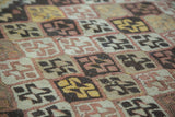 Hand woven Turkish kilim rug with repeating diamond motifs in earthen green, brown, and mauve.