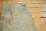 Faded celadon and pale peach geometric design with distressed pile on a vintage Oushak rug.