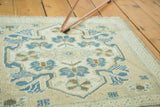 Hand-knotted Oushak rug's sand, ivory, and teal blue quatrefoil and corner pattern details.