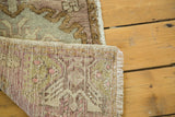 Vintage Oushak rug runner's hand-knotted back, with fringe and soft mauve, green, ivory tones.