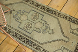 Corner of a vintage Oushak runner, showing charcoal scrolling vine border and geometric motifs.
