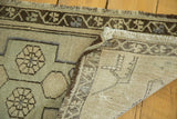 Hand-knotted Turkish Oushak rug corner, showing beige geometric pattern, fringe, and reverse weave.