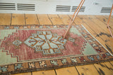 Angled detail of vintage Oushak rug mat, highlighting geometric patterns in burgundy, celadon, and coffee.