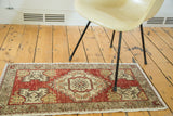 Distressed Oushak rug runner featuring cherry red, ivory floral motifs, and fringed edge.