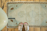 Vintage Oushak rug with faded celadon green field, stepped medallion, and brown wave border.
