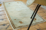 Fringed corner of vintage Oushak rug showing faded celadon green and brown wave motif border.