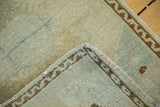 Folded vintage Oushak rug corner, showing unique brown wave motif and faded celadon field.
