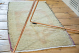 Evenly worn beige pile and secured edge of the vintage Oushak runner.