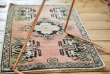 Vintage Oushak rug corner with germinating planter motif in peach pink, charcoal, and ivory.