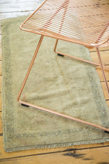 Vintage Oushak rug showing irregular weave, even wear, fringe, and oxidized copper green border.