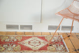 Angled view of vintage Oushak runner with cherry red, ivory, gold geometric corner design.