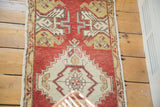 Stepped center medallion of this vintage Oushak runner, highlighting splayed floral motifs and warm colors.