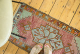 Vintage Oushak runner's end showing geometric border and fringe in muted cranberry, celadon tones.