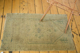 Distressed vintage Oushak rug texture, highlighting faded forest green outlines on a sand ground.
