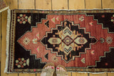 Vintage Oushak runner featuring a central geometric medallion in earthy red and dark brown. 1'8