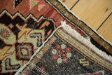 Folded corner of vintage Oushak rug, showing hand-knotted pile, geometric patterns, and foundation.