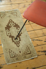 Rectilinear medallion with powerful rams horns in dark bronze on a beige Oushak rug.