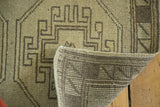 Close-up of a vintage Oushak rug showing brown geometric design, short pile, and hand-knotted back.