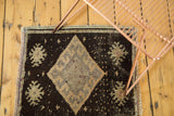 Corner of vintage Oushak rug displaying fringed edge, short pile, and charcoal diamond motif.
