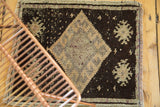 Vintage Oushak rug detail: dusty blush diamond medallion on charcoal field, partial view.