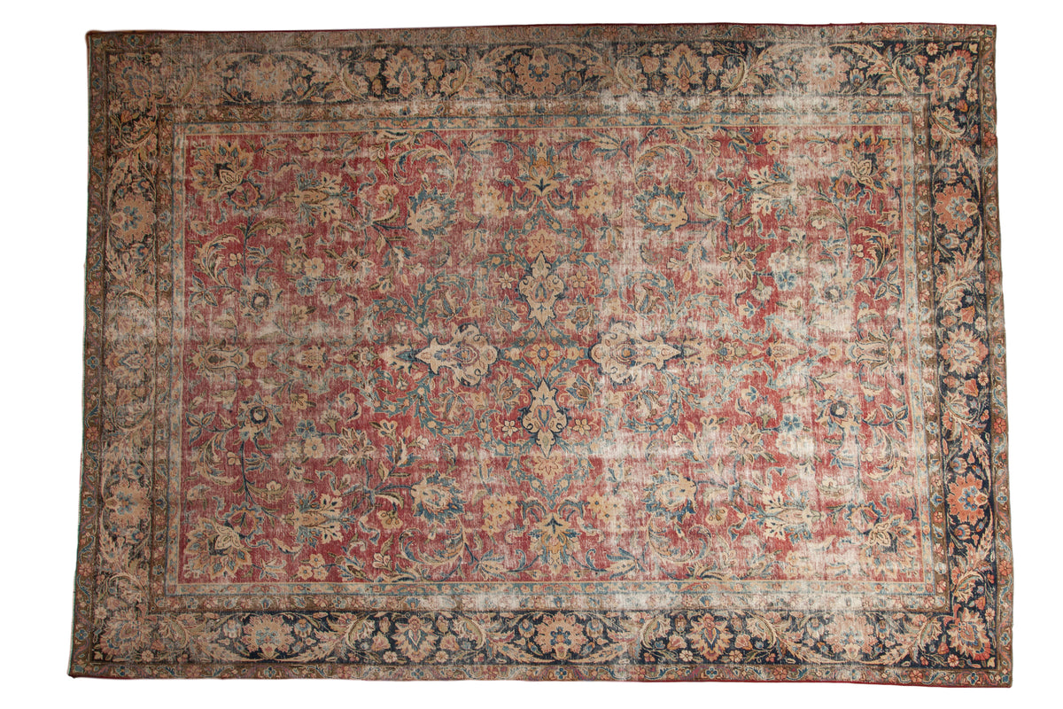 Distressed vintage Persian carpet, raspberry red field, subtle shadow medallion, navy floral border.